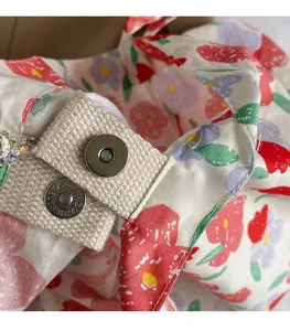 Detail of silver magnetic buckle closure on a floral canvas crossbody shopping bag