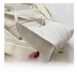 Detailed view of white quilted shoulder bag with golden buckle and fine stitching