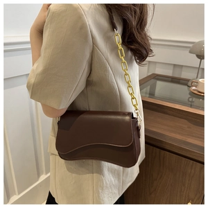Detail of dark brown leather handbag with curved bottom and chunky gold chain strap