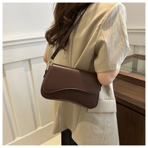 Detail of dark brown vintage shoulder bag featuring a unique wavy flap and gold hardware