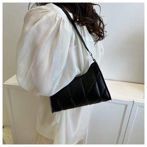 Detail of black quilted shoulder bag with diamond pattern and glossy faux leather finish