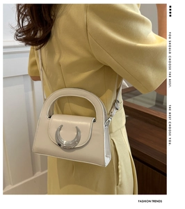 Detail of cream white leather moon bag featuring a silver metal buckle and top handle