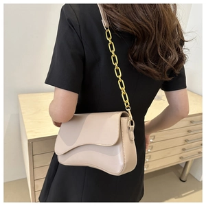 Nude beige underarm bag with gold chain strap and wave flap design on a model