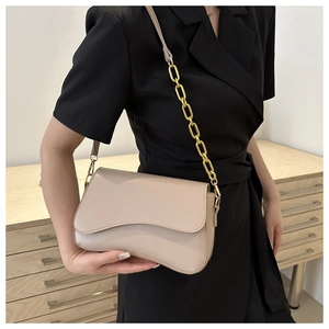Detail of beige crossbody bag with wavy flap design and chunky gold chain strap