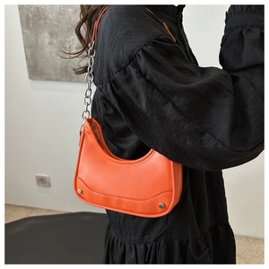 Detail of bright orange crescent hobo bag with silver chain strap and matte leather