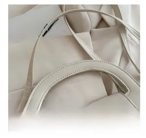 Close-up of beige handbag featuring hollow ring handle and silver crescent buckle detail