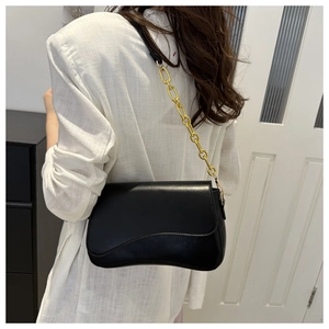 Detail of black leather shoulder bag with vintage curved base and gold chain strap