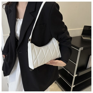 Close-up of a white quilted shoulder bag styled with a professional black blazer