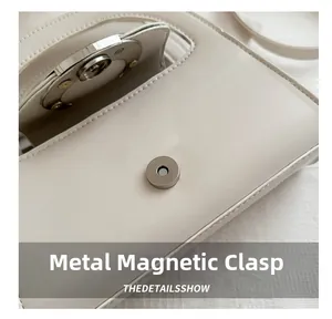 Detailed macro view of the silver magnetic closure on a beige leather crescent handbag