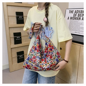 Detail shot of a large floral nylon tote bag featuring vibrant red and yellow patterns