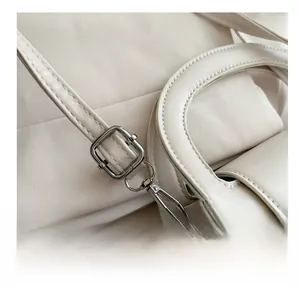 Detail of adjustable off-white PU leather shoulder strap with silver metal buckle and hook