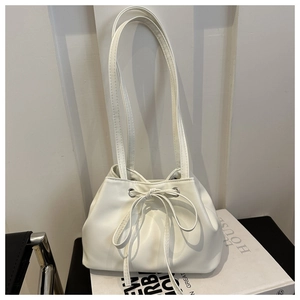 Dettaglio di una borsa a secchiello in pelle bianca con coulisse, fiocco e occhielli