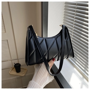 Detail of black quilted faux leather shoulder bag with gold zipper and textured surface