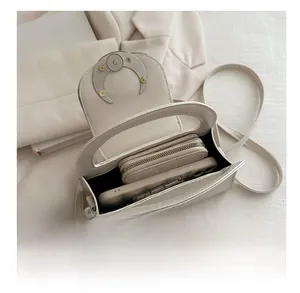 Interior detail of a beige half-moon bag showing storage space for phone and wallet