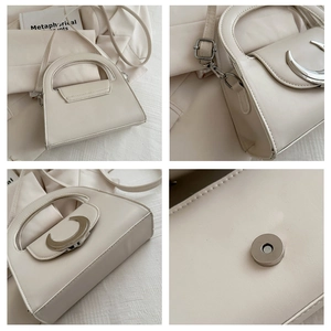 Detail view of cream faux leather handbag with silver moon buckle and magnetic closure