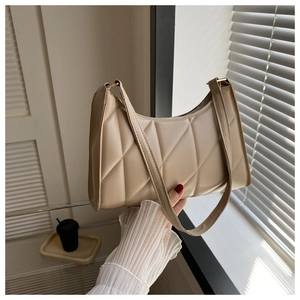 Macro view of beige quilted leather shoulder bag featuring fine stitching and metal buckles