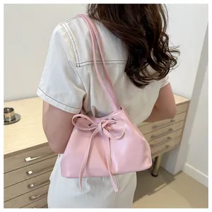Detail of pink PU leather bucket bag featuring elegant drawstring bow and slim straps