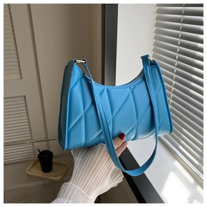Close-up of bright blue quilted leather shoulder bag with diamond stitch and gold hardware