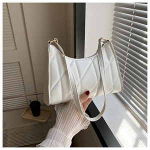 Detailed view of white quilted underarm bag with elegant gold metal ring accents