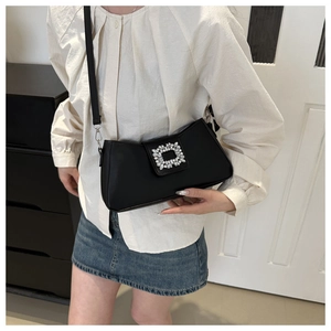Detail of a chic black leather underarm bag with a sparkling crystal square buckle