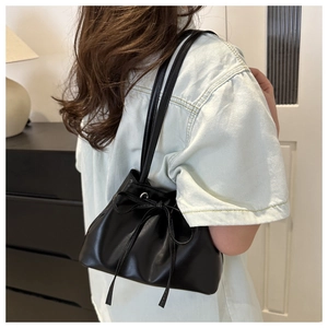Dettaglio della borsa a secchiello in PU nero con design a pieghe e un fiocco elegante