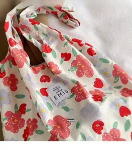 Primer plano de bolsa tote de lona floral con etiqueta EMIS y patrón de flores de colores