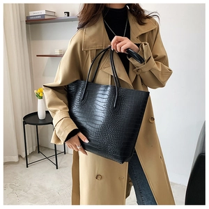 Model wearing black crocodile pattern tote bag with long handles and a sleek trapezoid shape
