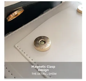 Detail of a round gold magnetic clasp with woven texture on an off-white leather bag