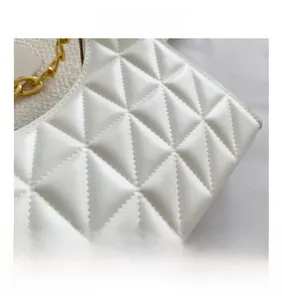 Close-up of white quilted leather texture and chunky gold chain strap on shoulder bag