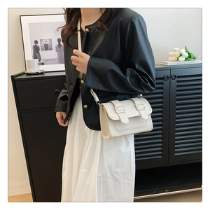 Close-up of minimalist cream white square crossbody bag with decorative strap buckles