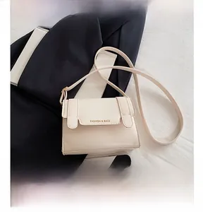 Detail view of cream leather crossbody bag with adjustable strap and gold fashion logo