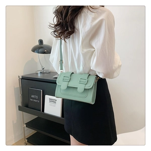 Detail of mint green leather crossbody bag with double buckle and gold hardware