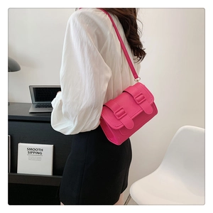 Detail of hot pink crossbody square bag with double buckles in a modern office setting