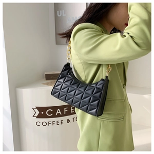 Close-up of black quilted leather shoulder bag with decorative thick gold chain strap