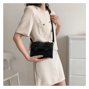 Close-up of minimalist black leather crossbody bag with dual straps and gold hardware
