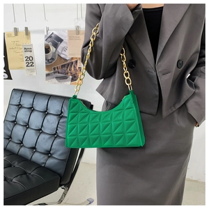 Detail of quilted bright green underarm bag with thick gold chain worn by a model