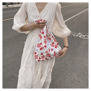Detalle de bolso de lona floral con etiqueta EMIS y vestido blanco con cuello en V