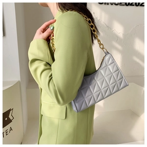 Quilted lavender grey baguette bag with chunky gold chain strap worn by a model