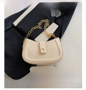 Detail view of cream crescent bag with gold chain strap and square magnetic buckle
