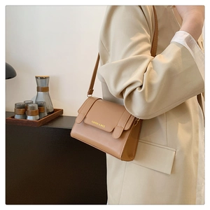 Close-up of tan leather crossbody bag with golden Fashion & Bags logo and shoulder strap