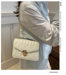 Detail showing white quilted leather texture and gold twist-lock closure on small square bag