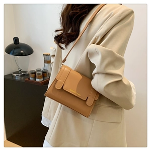Chic khaki faux leather crossbody bag with flap and gold lettering on model in beige suit