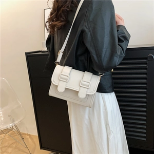 Minimalist white leather rectangular shoulder bag worn by model over a black jacket