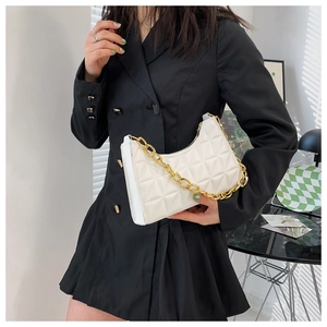 Detail of a beige quilted hobo bag with a chunky gold chain strap worn on the shoulder