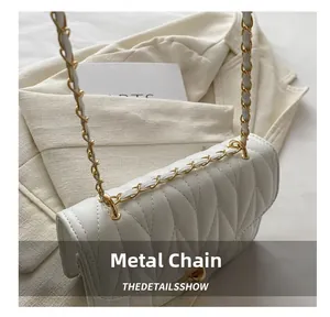 Détail de la bandoulière en chaîne dorée sur un sac bandoulière en cuir blanc matelassé