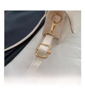 Détail de la bandoulière en similicuir crème avec boucle réglable en métal doré