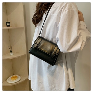 Close-up of black leather crossbody bag with gold text on white shirt model