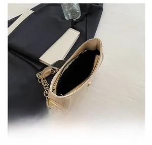 Interior view of beige leather shoulder bag showing black lining and zip pocket with gold chain