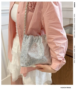 Silver sequin crossbody bag with chain strap shown on model in a stylish indoor setting