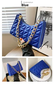 Detail of blue quilted shoulder bag with geometric stitching and chunky gold chain strap